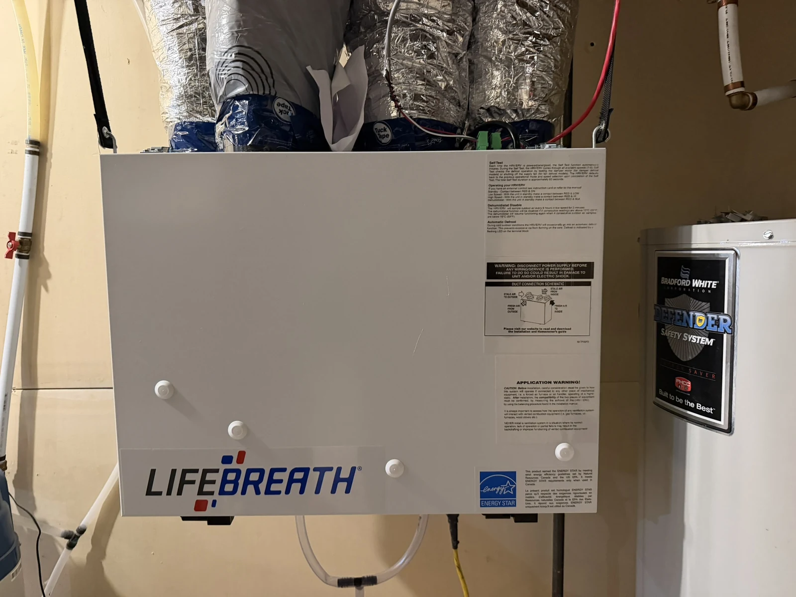 Residential HVAC Calgary: a Lifebreath HRV installed beside the hot water tank in a Calgary basement