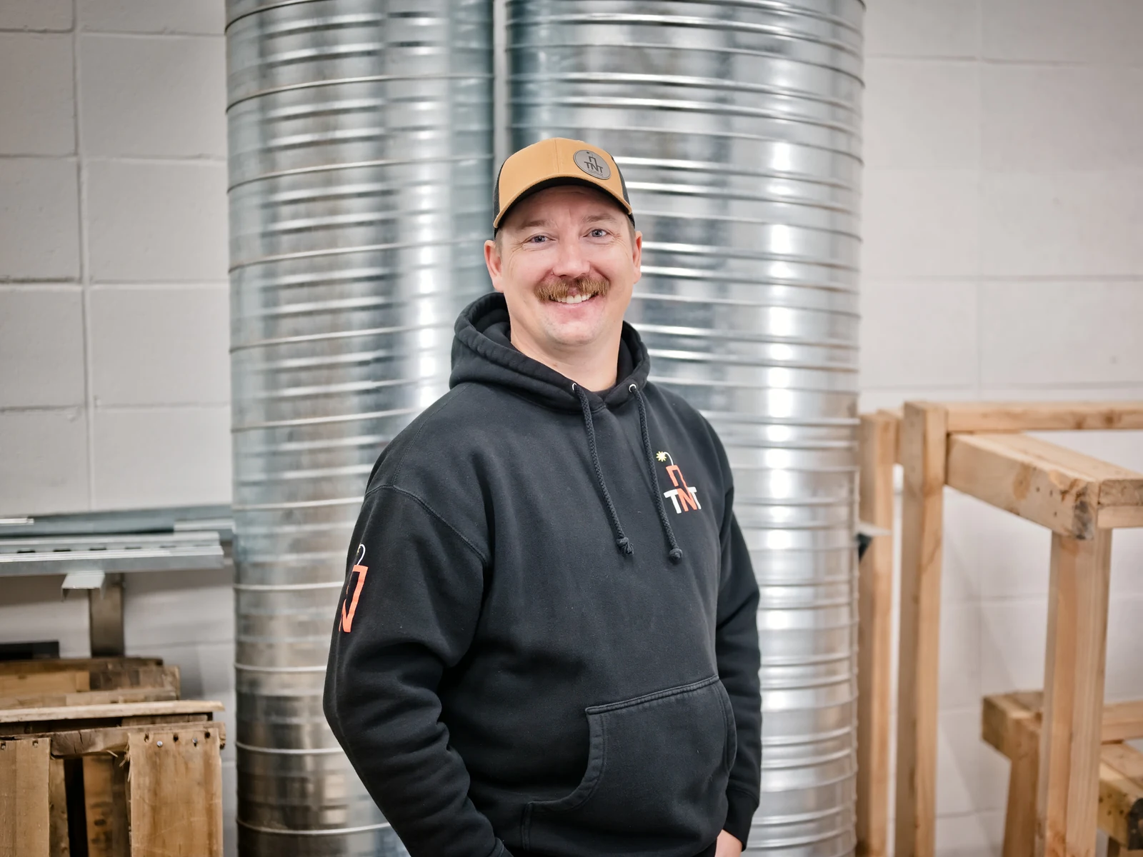 Residential HVAC Calgary: one of the TNT owners standing beside spiral duct in the Calgary shop