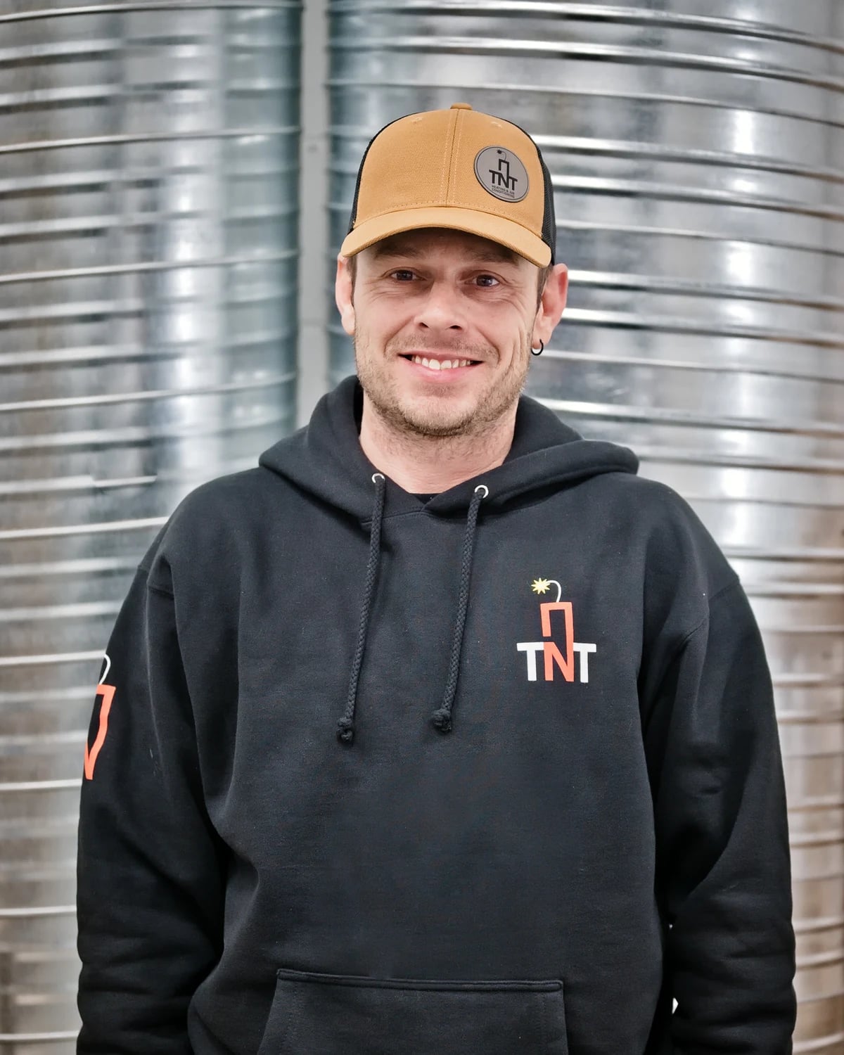 AC repair Calgary: one of the TNT owners smiling in the shop in front of spiral duct