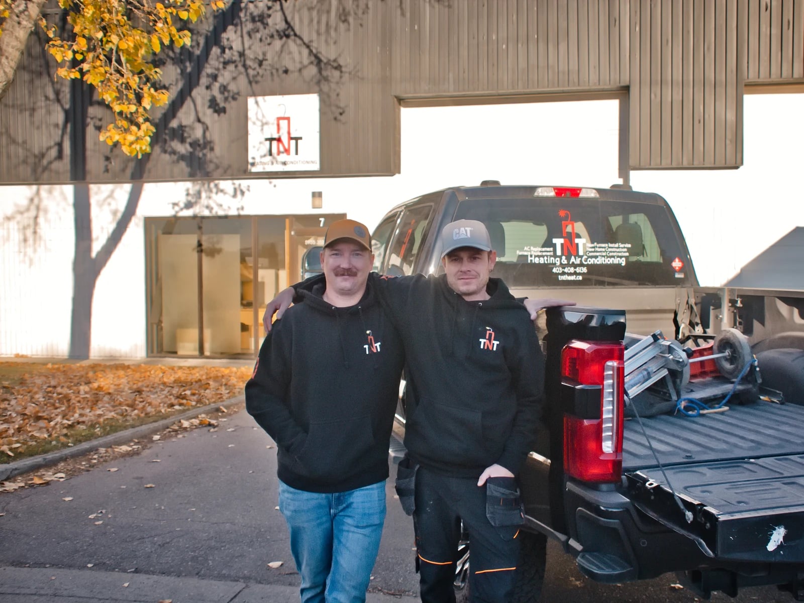 HVAC financing Calgary: the two TNT owners with a TNT truck outside their Calgary shop