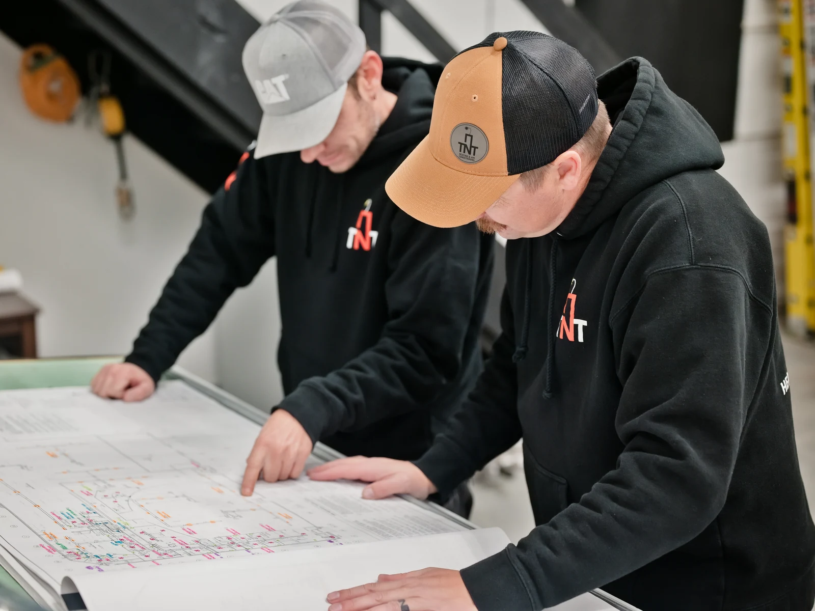 HVAC services Calgary: the two TNT owners going over a set of mechanical drawings at the plan table