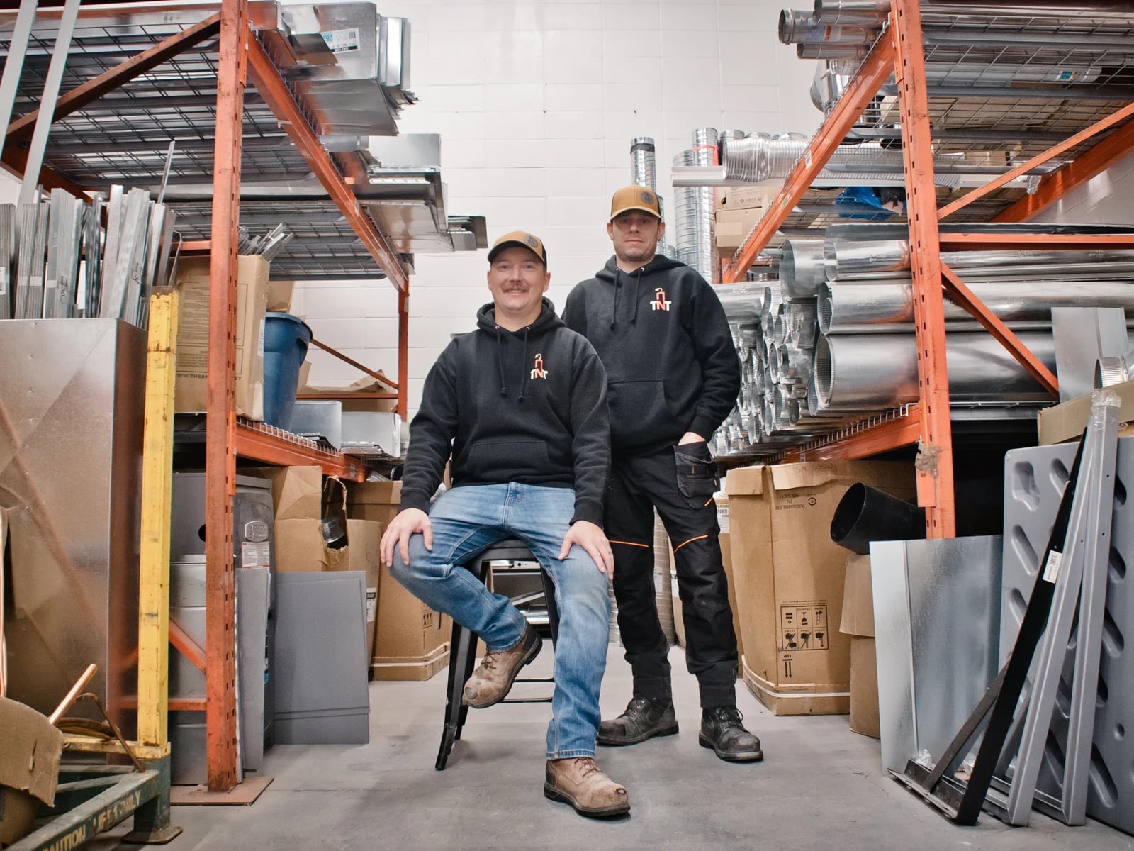 HVAC services Calgary: the two TNT owners among the duct and sheet metal racking in their Calgary shop