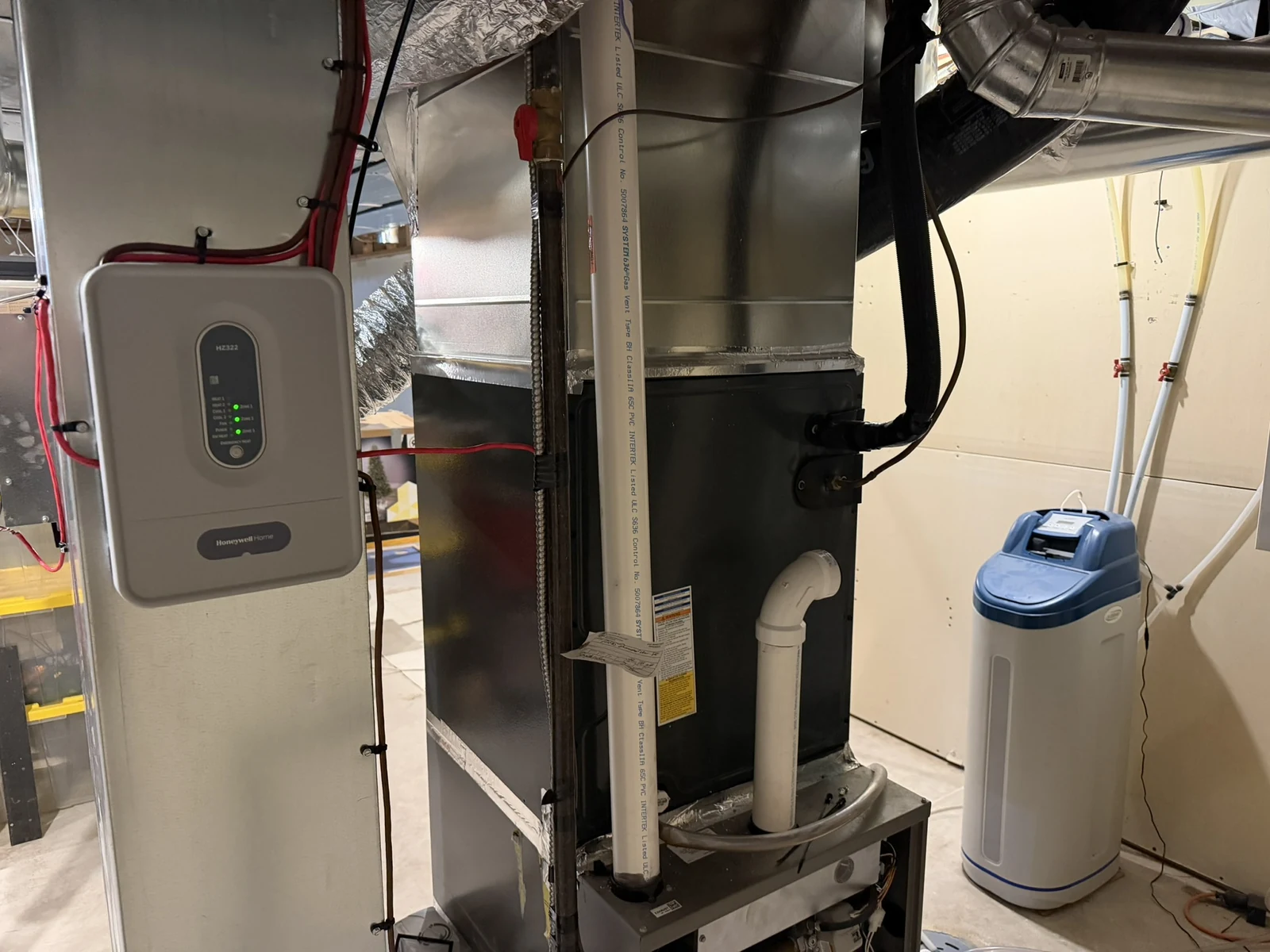 Residential HVAC Calgary: a zone control panel beside a furnace and its ductwork in a Calgary basement